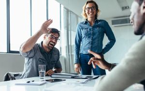 Businessman offering a high five to a coworker during a meeting in conference room