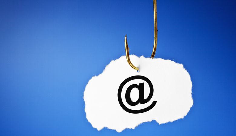 Email symbol printed on a piece of paper hooked on a fishing hook shows phishing and data protection concept